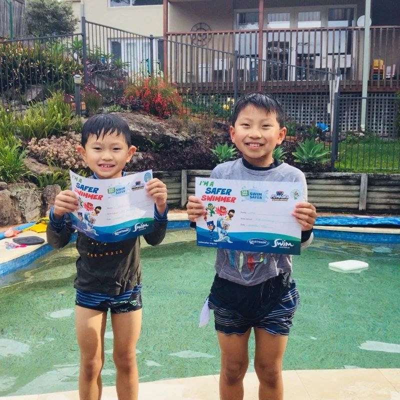 Two kids holding their Swim Safer Week certificates